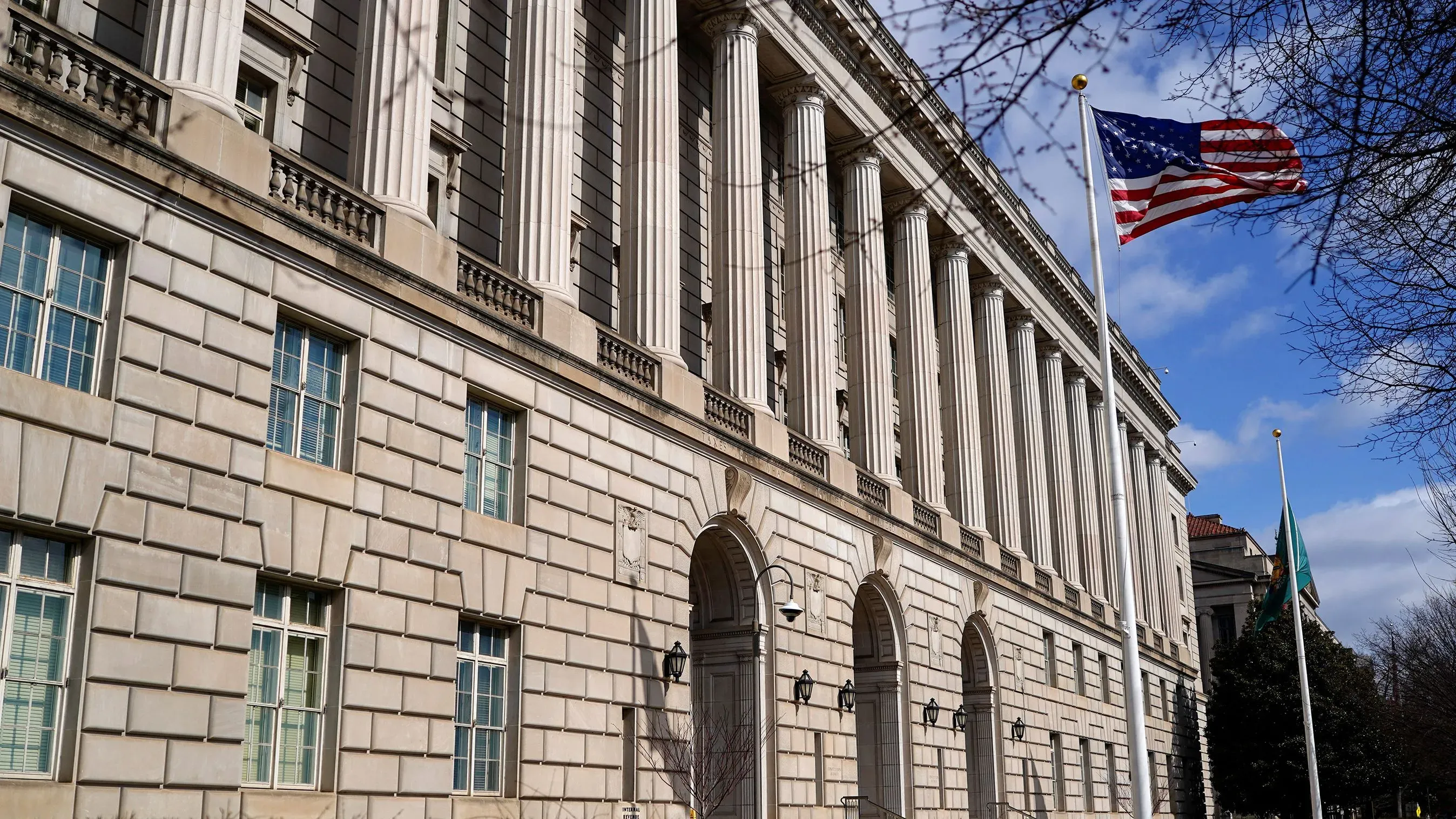 مبنى مصلحة الضرائب الأمريكية بواجهة كلاسيكية، يظهر العلم الأمريكي يرفرف في المقدمة، يعكس التوترات حول معلومات المهاجرين غير الموثقين.