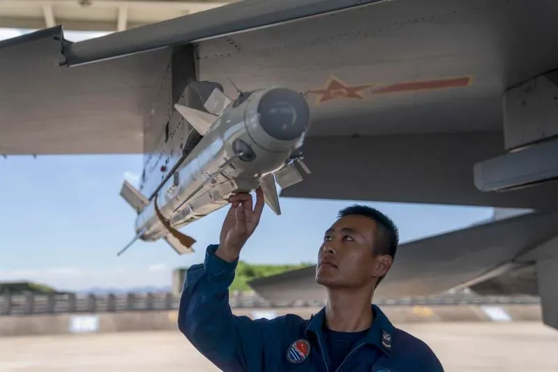 فني صيني يقوم بفحص صاروخ موجه مثبت على طائرة حربية، في سياق تعزيز القدرات العسكرية للصين.