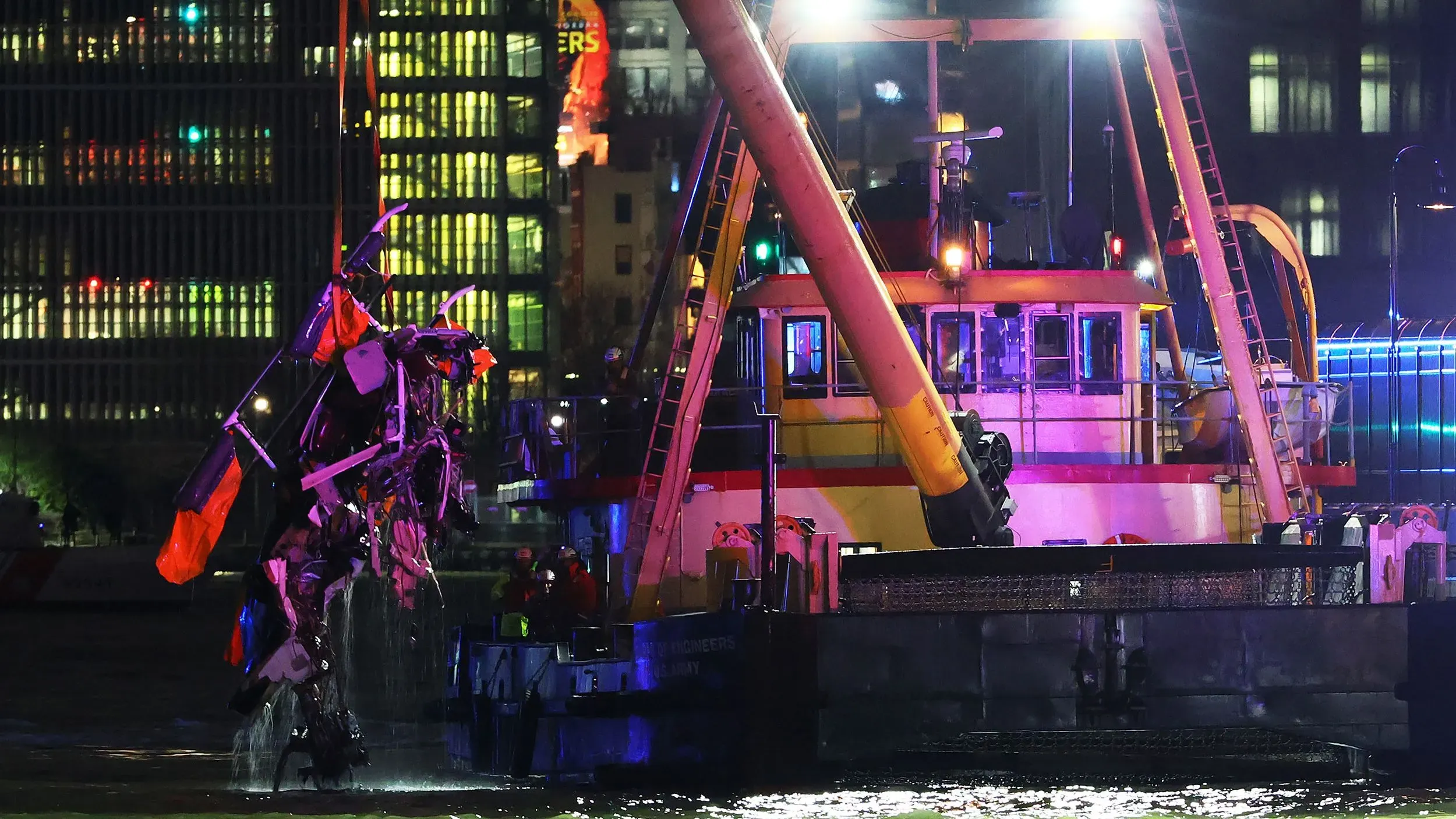 رفع حطام مروحية سياحية من نهر هدسون بعد تحطمها، مع وجود قارب إنقاذ في الخلفية وأضواء ملونة تعكس على الماء.