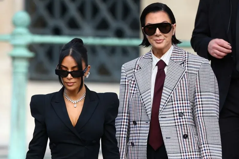 كايلي جينر وكريس جينر تتجهان معًا في حدث، حيث ترتدي كايلي بدلة سوداء وكريس ترتدي سترة مربعة مع نظارات شمسية، تعكسان أسلوبهما الأنيق.