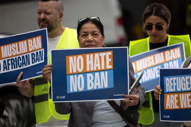 متظاهرون يحملون لافتات تعبر عن معارضتهم لحظر السفر، مع شعارات مثل "لا كراهية لا حظر" و"حظر المسلمين".