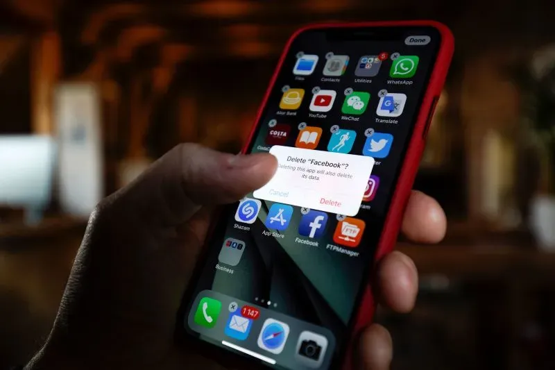 شخص يمسك بهاتف ذكي، يظهر على الشاشة إشعار لحذف تطبيق فيسبوك، مما يعكس التحديات المرتبطة بالتخلي عن وسائل التواصل الاجتماعي.
