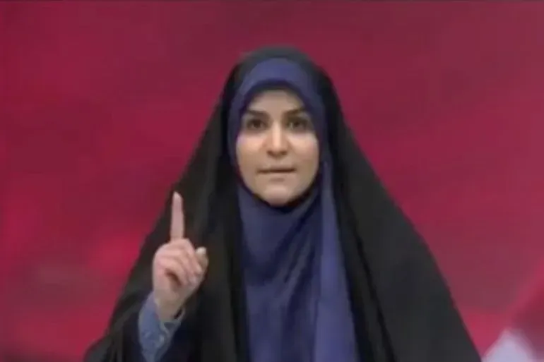 مذيعة إيرانية تُدين العدوان الإسرائيلي على وطنها خلال بث مباشر، وسط دخان وحطام بعد انفجار استهدف هيئة الإذاعة والتلفزيون الإيرانية.