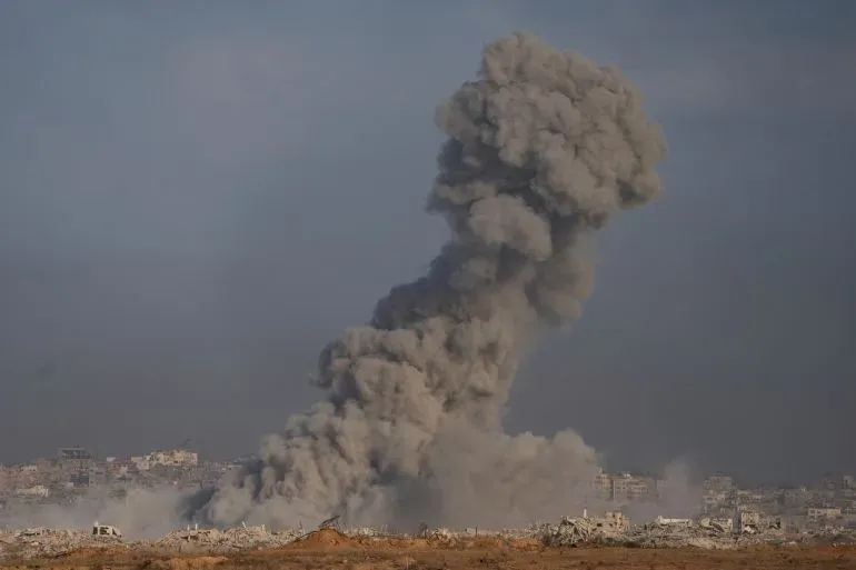 سحابة ضخمة من الدخان تتصاعد في سماء غزة بعد قصف عسكري، مع تدمير العديد من المباني في المنطقة.