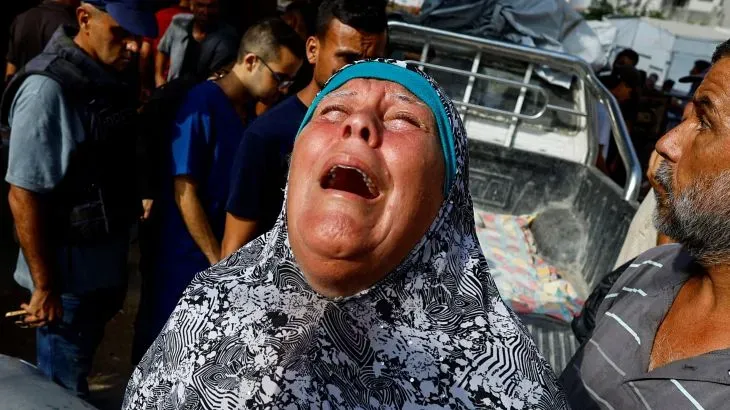 امرأة تبكي بحرقة وسط تجمع من الناس في غزة بعد الهجوم الإسرائيلي، تعبيرًا عن الحزن لفقدان عائلتها.