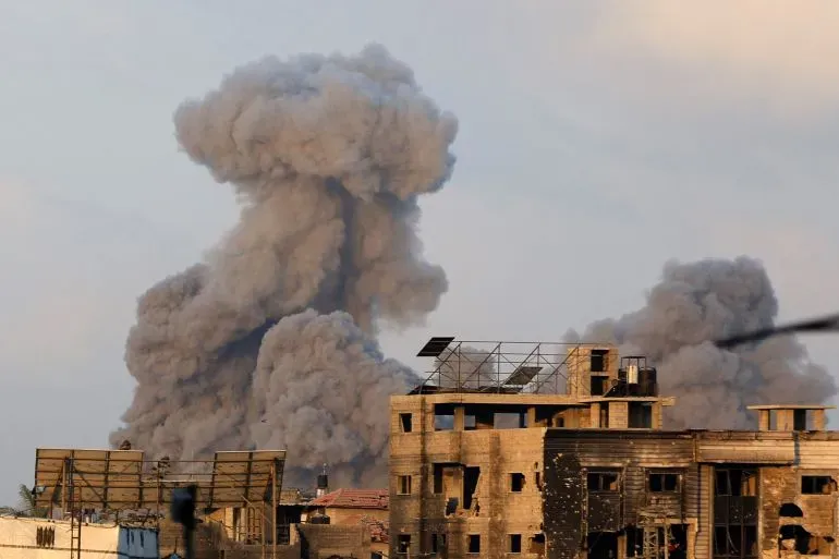 تصاعد سحب من الدخان الكثيف فوق المباني المدمرة في غزة بعد غارة جوية، مما يعكس تصاعد العنف والدمار في المنطقة.