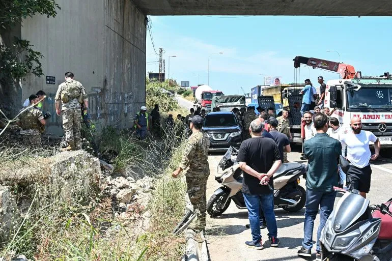تجمع عدد من الأشخاص، بينهم عسكريون، تحت جسر في لبنان بعد الهجمات الإسرائيلية، مما يعكس حالة من الفوضى والقلق في المنطقة.