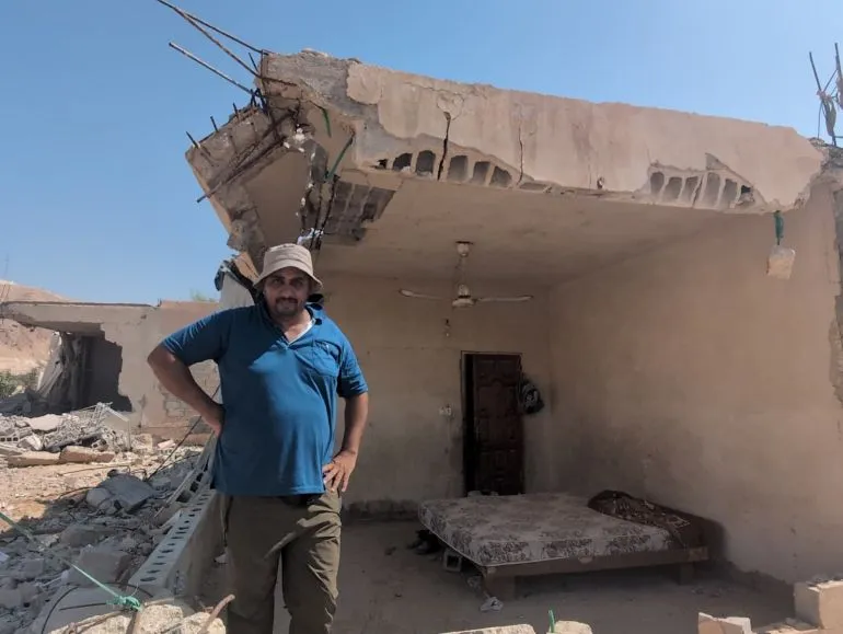 رجل فلسطيني يقف في غرفة مهدمة جزئياً بمنزل في حي الستيح بأريحا، يعكس آثار الهجمات الاستيطانية والهدم المستمر.