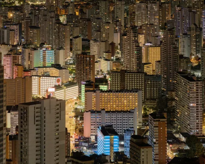 بينيدورم ليلاً، تظهر ناطحات السحاب اللامعة والمباني الحديثة، تعكس التحول السياحي للمدينة من بلدة صغيرة إلى وجهة شهيرة.