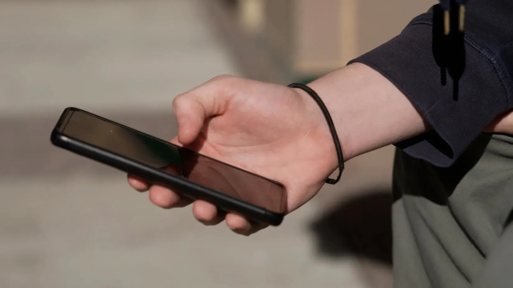 يد تحمل هاتفًا محمولًا، مما يعكس التحديات التي يواجهها الطلاب في مدرسة ويكفيلد الثانوية مع سياسة حظر الهواتف.