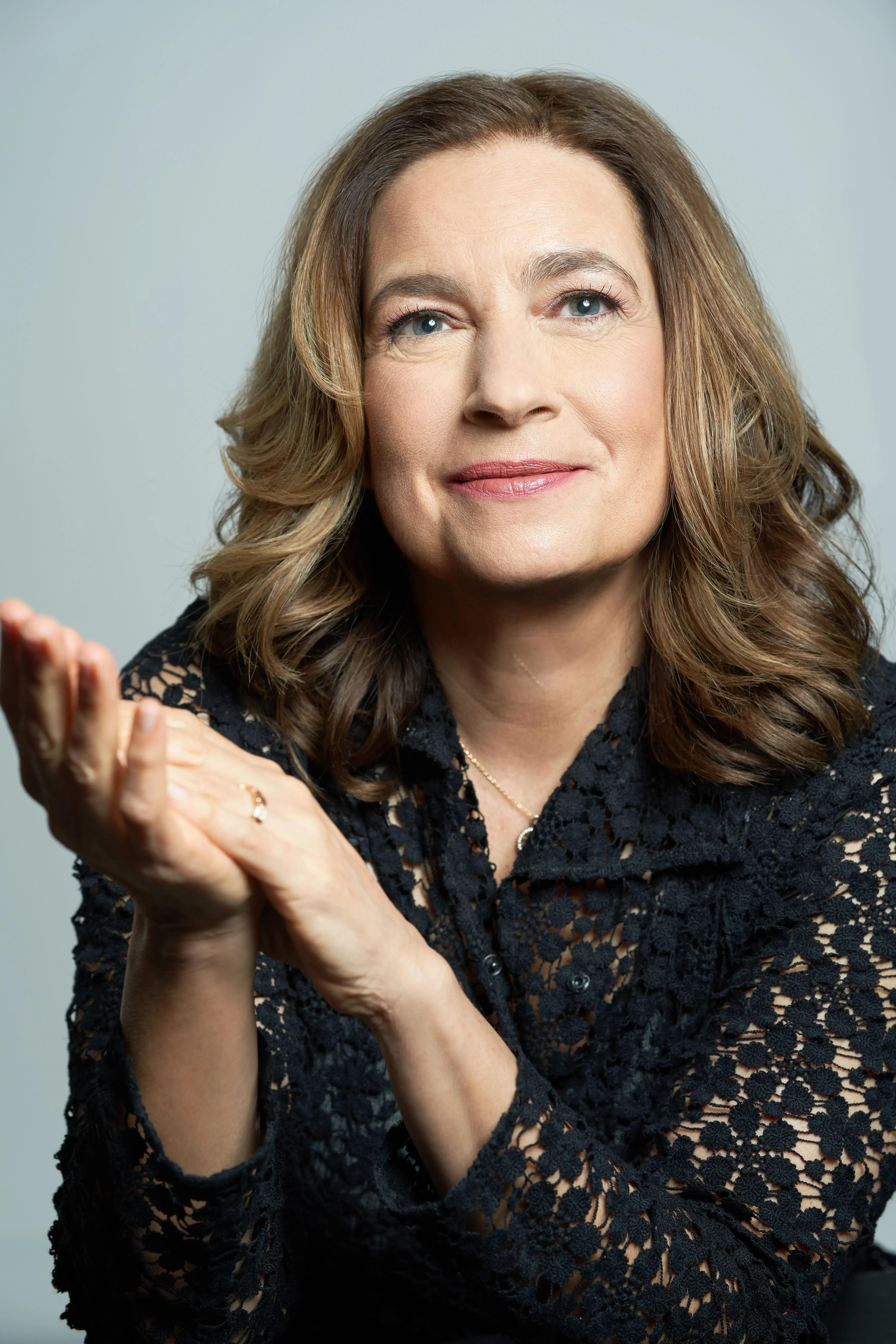 امرأة في منتصف العمر ترتدي قميصًا أسود من الدانتيل، تعبر عن مشاعرها بإيماءات يديها، تعكس موضوع الكتاب عن عواطف الآباء.