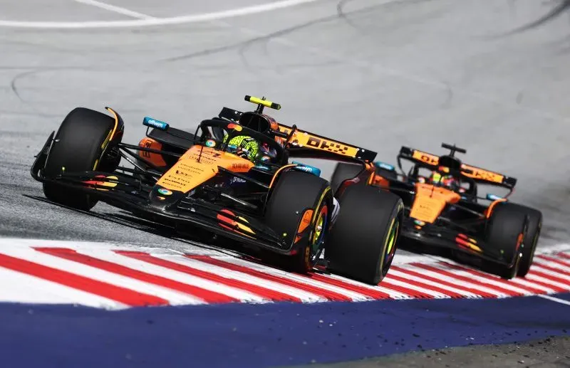 سيارتا مكلارين تتنافسان في سباق فورمولا 1، حيث يتقدم لاندو نوريس على زميله أوسكار بياستري في منعطف حلبة سريعة.