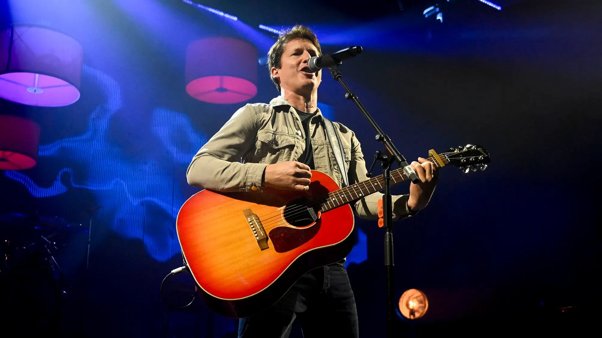 جيمس بلانت يؤدي أغنيته الشهيرة "أنت جميلة" على المسرح، مع إضاءة خلفية ملونة وجو مفعم بالطاقة.