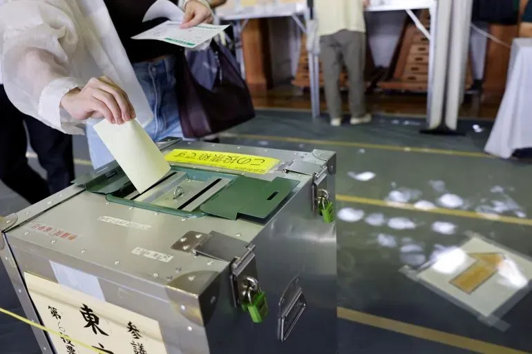ناخب يضع ورقة الاقتراع في صندوق في مركز اقتراع بطوكيو، وسط أجواء انتخابية تتسم بالقلق حول مستقبل الحكومة اليابانية.