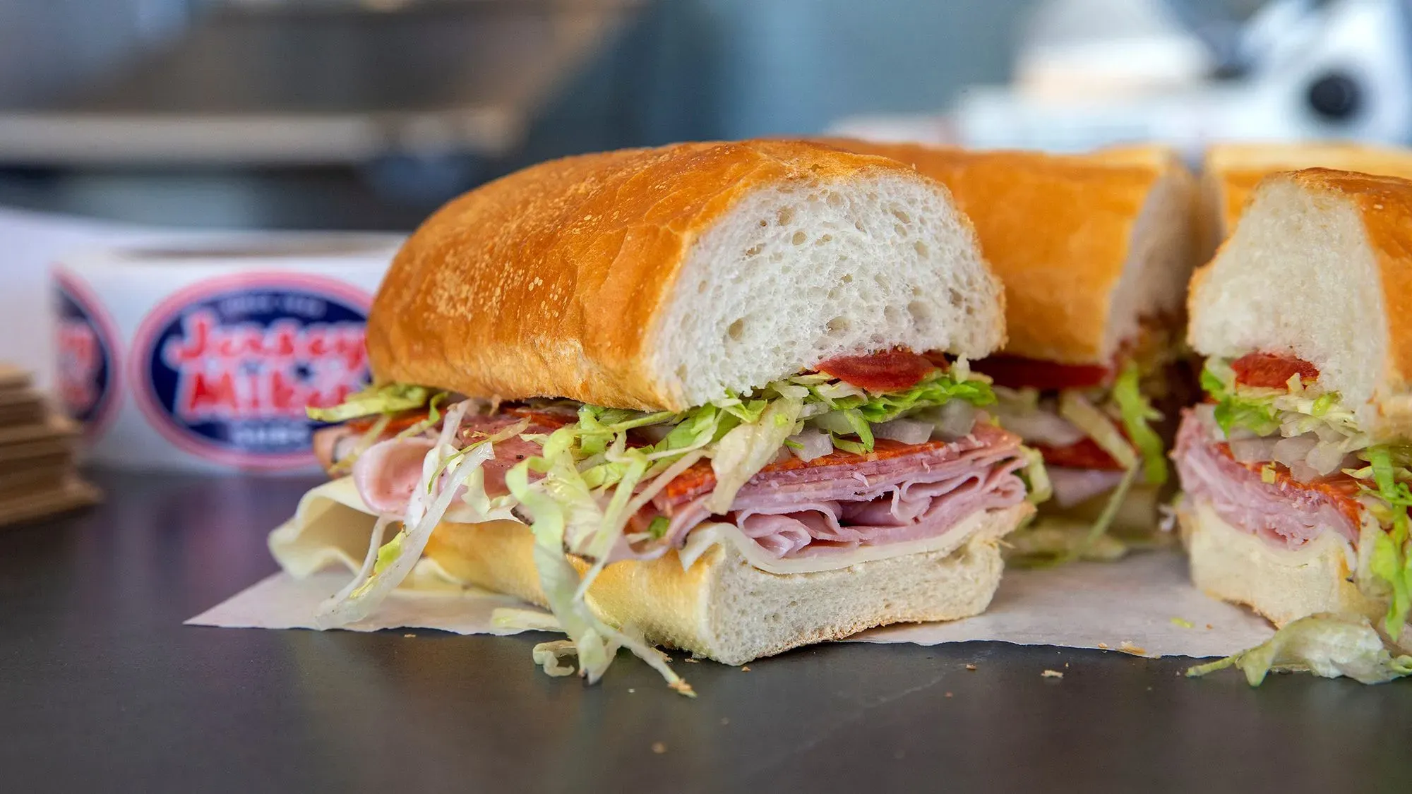 ساندويتش شطائر من سلسلة جيرسي مايك، يظهر الخبز الطازج مع مكونات متنوعة مثل اللحم والخس، في سياق إعلان عن تغيير القيادة في الشركة.