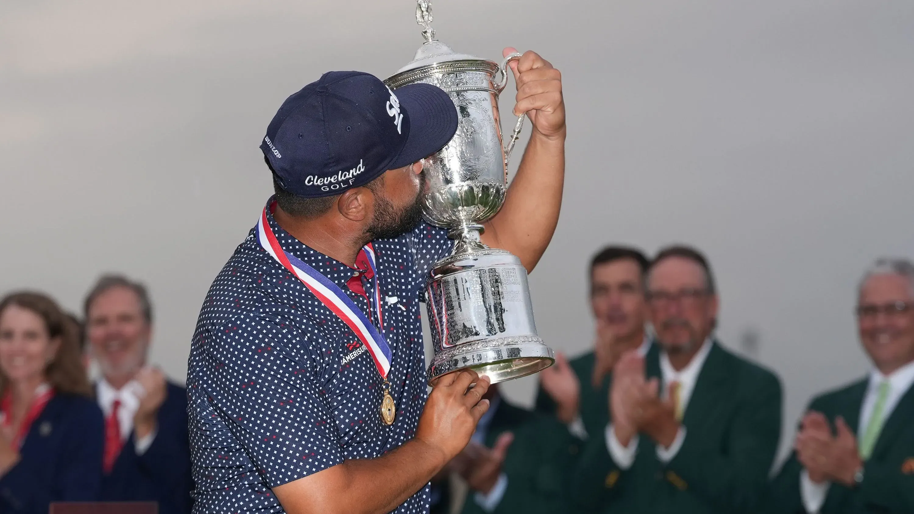 سباون يحتفل بفوزه ببطولة الولايات المتحدة المفتوحة، ممسكًا بالكأس بينما يصفق له الحضور. لحظة فارقة في مسيرته الرياضية.