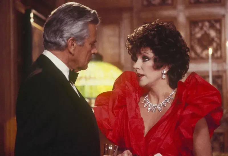 جوان كولينز ترتدي فستانًا أحمر مبهر وتظهر في مشهد حواري مع شخصية أخرى، مما يعكس أجواء درامية من فيلم "النهاية المريرة".