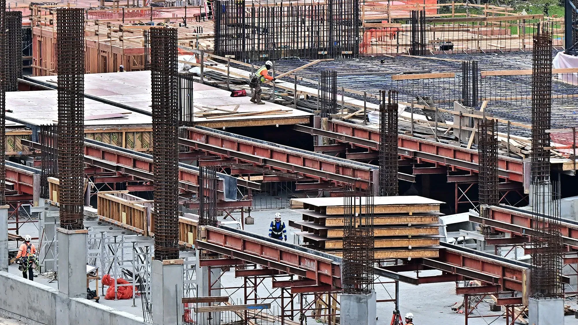 تظهر الصورة مشهدًا لموقع بناء مع عمال يجري العمل على الهياكل، مما يعكس نشاط سوق العمل في ظل تراجع فرص العمل في فبراير.