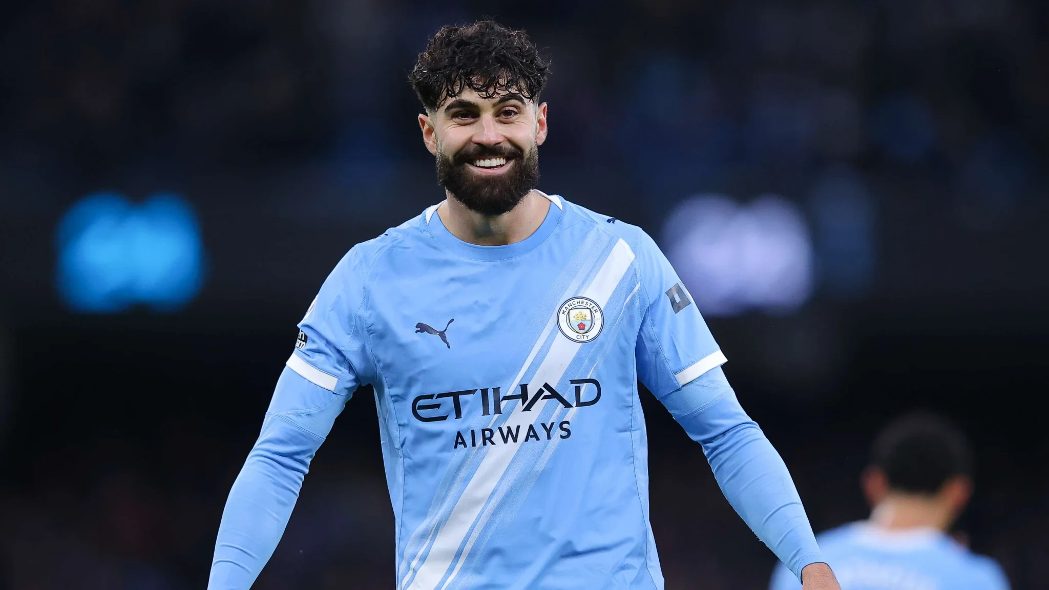لاعب مانشستر سيتي Josko Gvardiol يبتسم مرتديًا قميص الفريق الأزرق خلال مباراة، مع تجديد عقده حتى 2031.