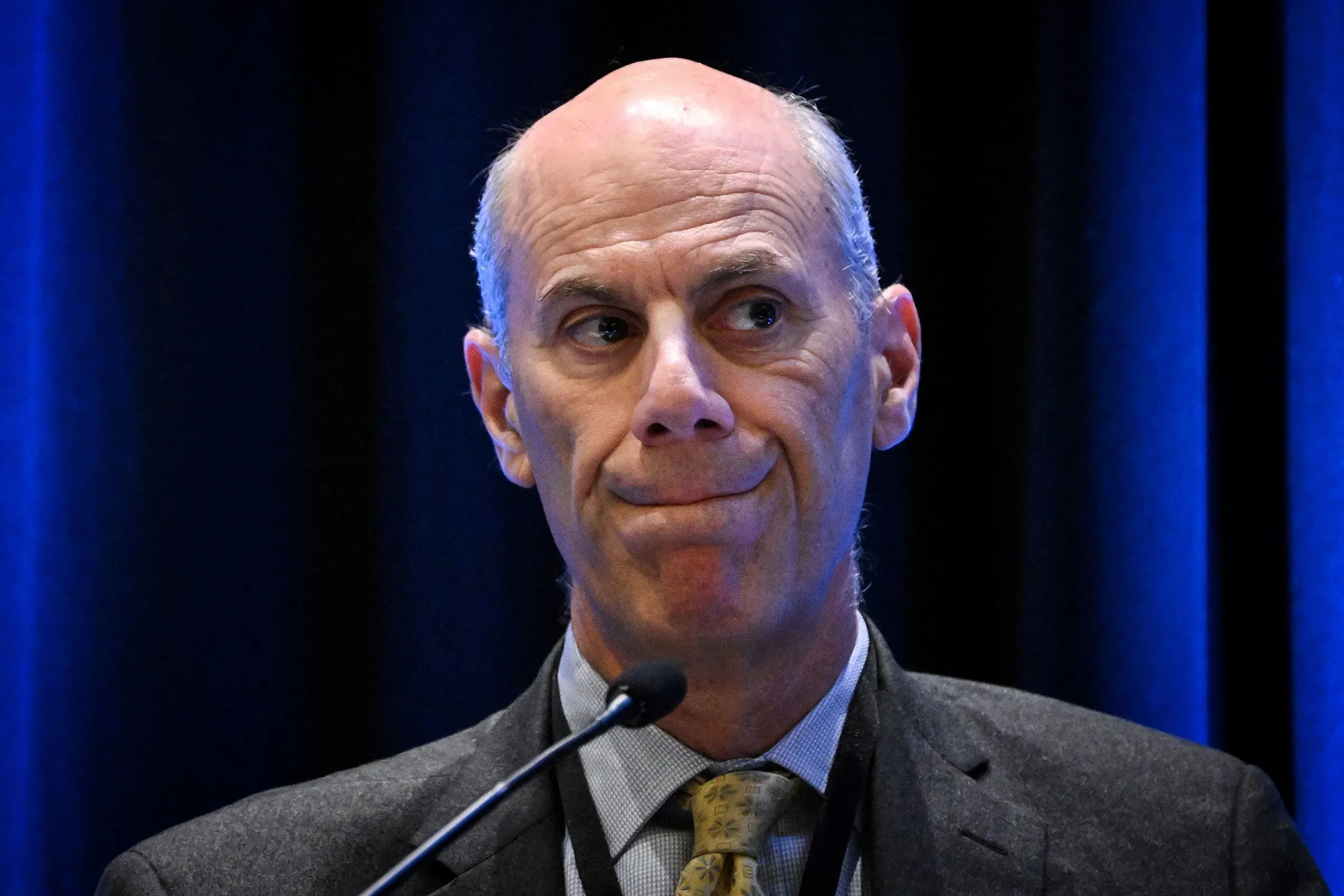 تعبير عن القلق على وجه محامي وزارة العدل درو إنسيجن خلال مؤتمر، وسط تساؤلات حول قرارات ترحيل المهاجرين.