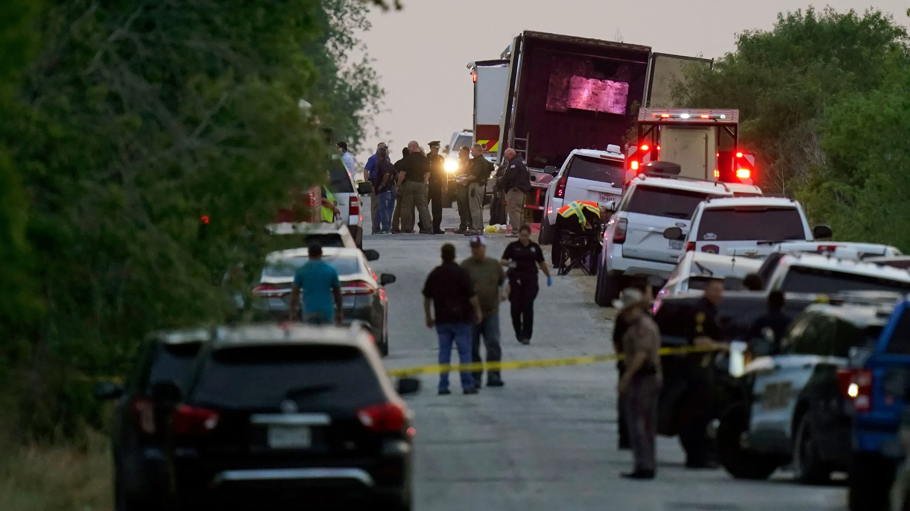 موقع الحادث حيث تم اكتشاف 53 مهاجرًا متوفى في شاحنة في سان أنطونيو، مع وجود الشرطة والإسعاف في مكان الحادث.