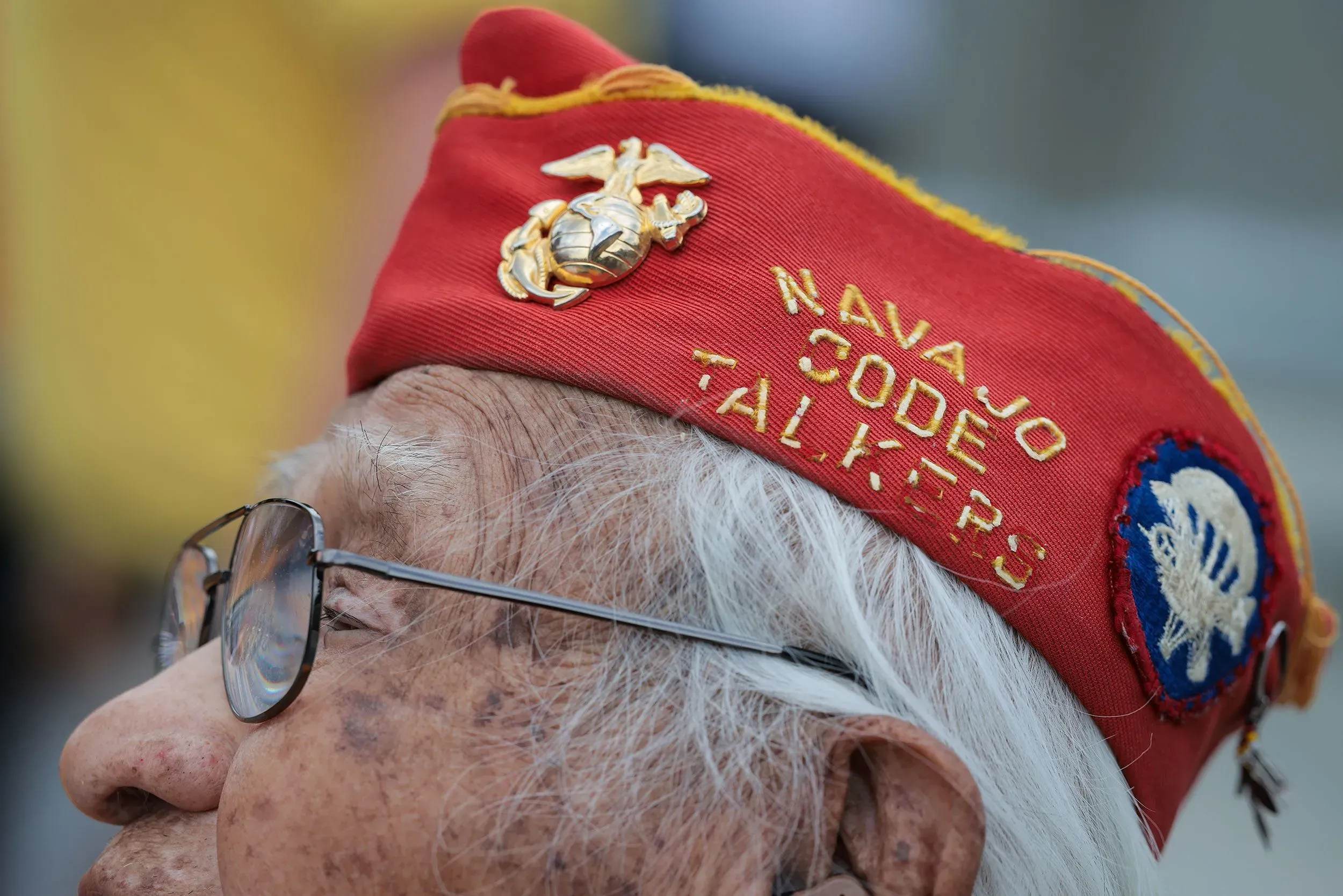 قبعة تحمل شعار "متحدثي شفرة نافاجو" على رأس رجل مسن، تعكس إرثه كأحد المحاربين القدامى الذين ساهموا في الحرب العالمية الثانية.