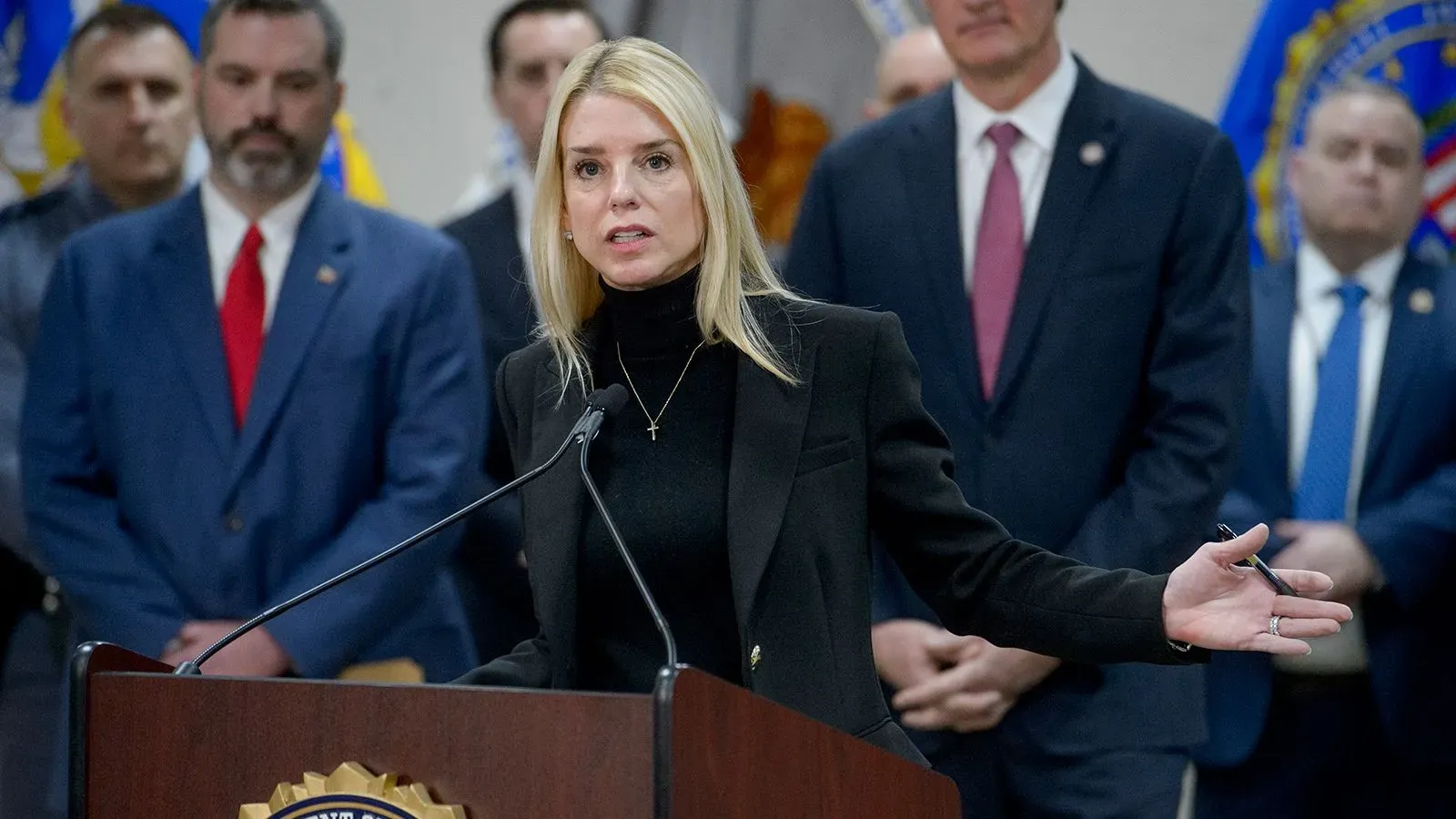 المدعي العام بام بوندي تتحدث في مؤتمر صحفي حول إسقاط التهم ضد زعيم عصابة إم إس-13، مع وجود مسؤولين آخرين خلفها.