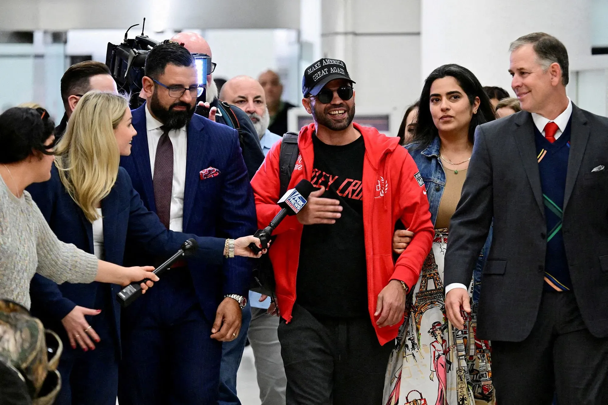 مجموعة من الأشخاص، بينهم زعيم "براود بويز" السابق، يتحدثون مع الصحفيين في مطار بعد صدور حكم قضائي.