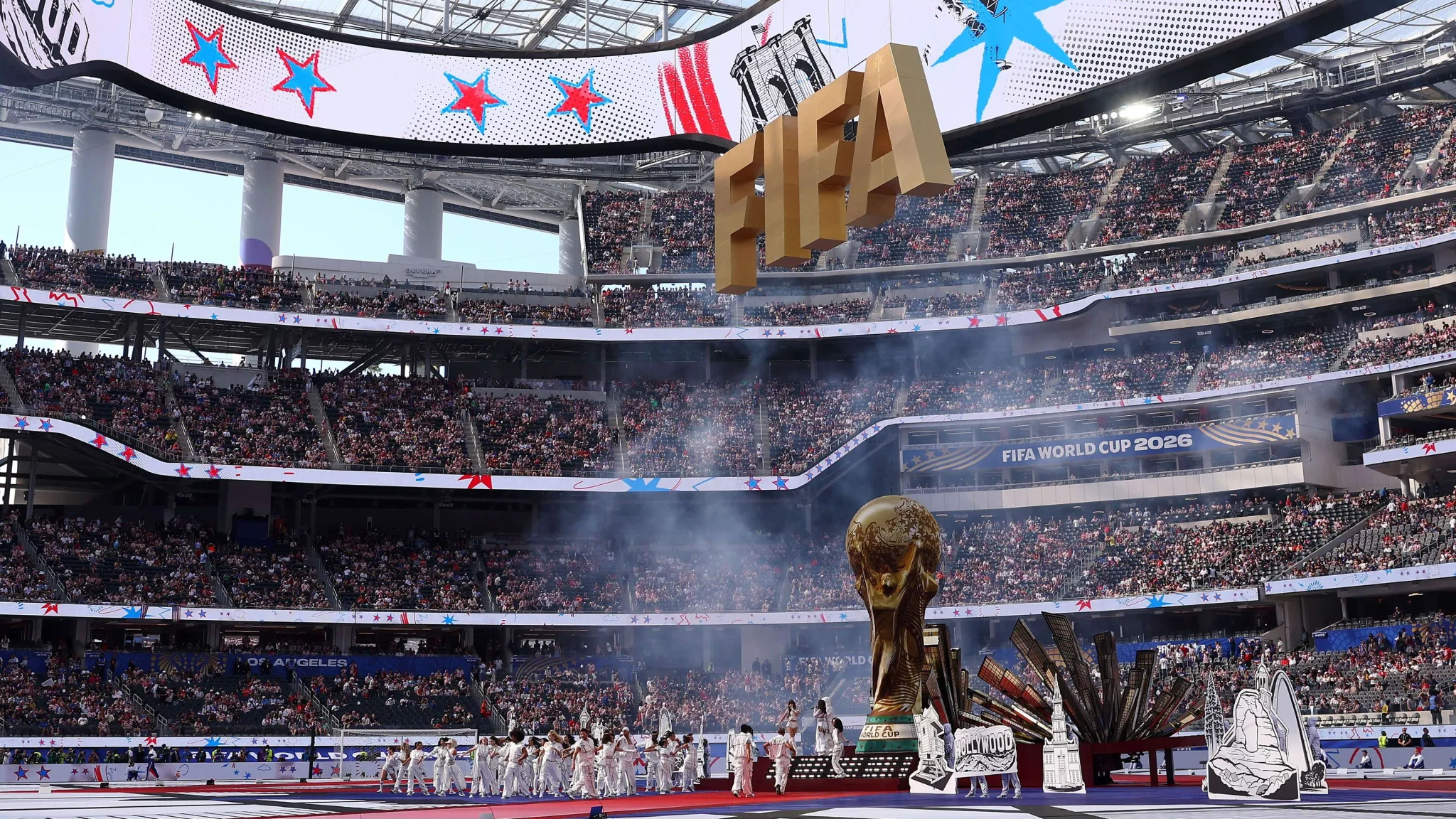 ملعب كرة قدم ضخم مكتظ بالجماهير مع عرض فني ضخم ونهائي كأس العالم 2026 تحت شعار FIFA ودعم التعليم للأطفال.