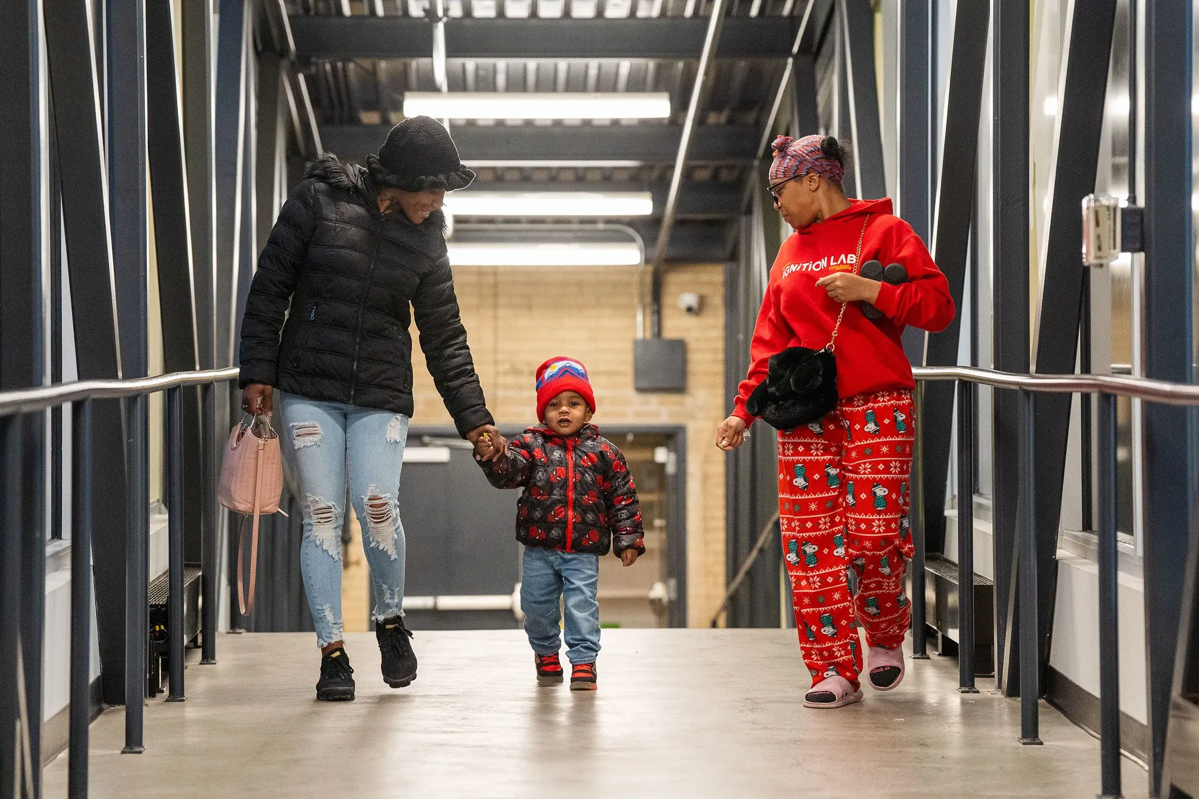 امرأتان وطفل يسيرون معًا على ممر فوق جادة تروست في مدينة كانساس سيتي، مما يرمز إلى جهود التوحيد المجتمعي.