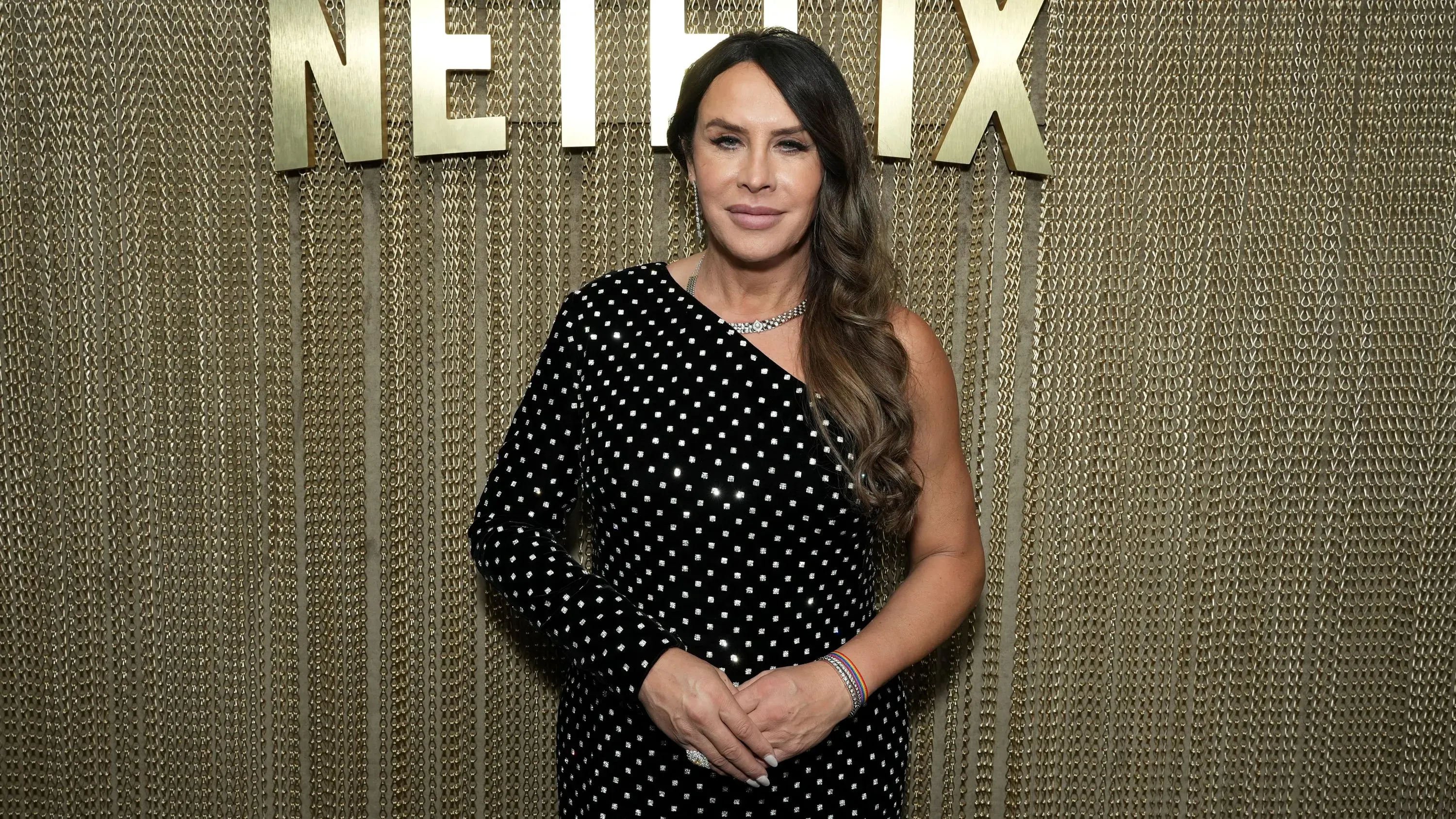 كارلا صوفيا غاسكون ترتدي فستانًا منقطًا باللون الأسود، تقف أمام خلفية تحمل شعار نتفليكس، تعبر عن امتنانها لترشيحها للأوسكار.