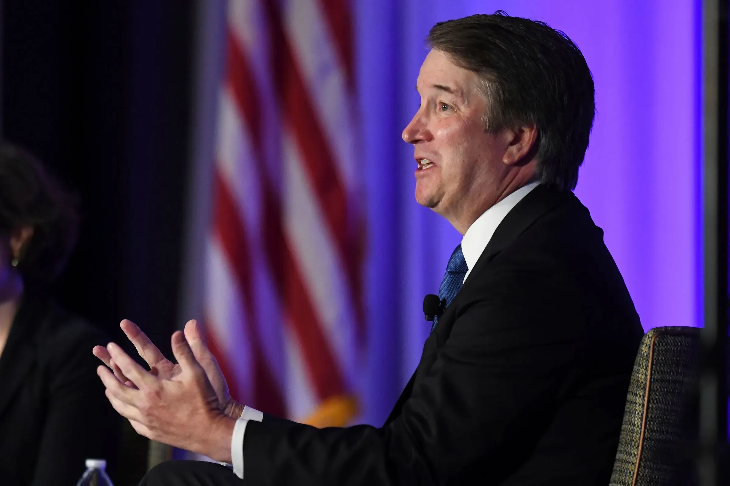 القاضي بريت كافانو يتحدث خلال حدث، مع العلم الأمريكي في الخلفية، حول قضايا حقوق الإنسان والهجرة.