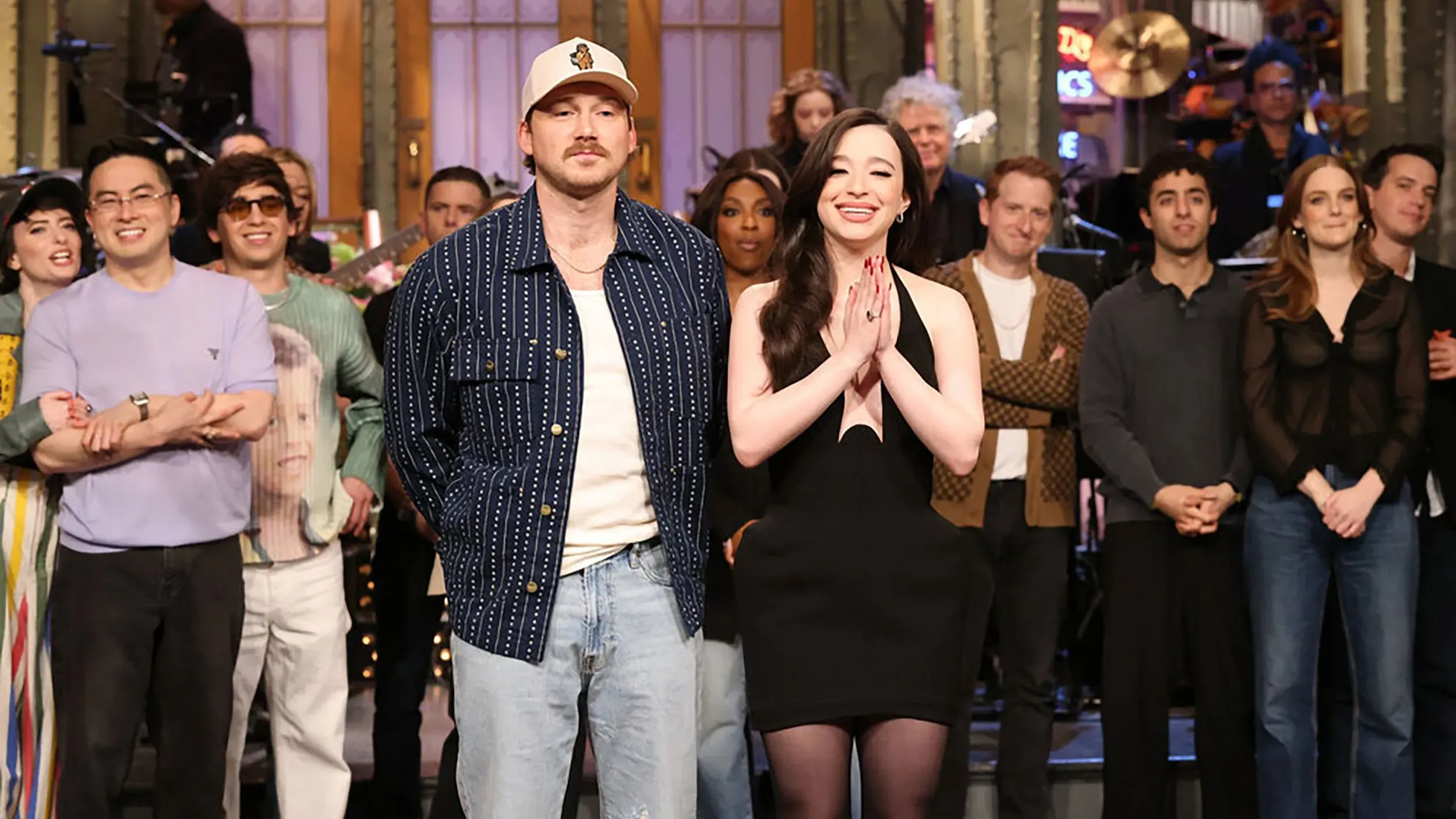 كينان طومسون ومورغان والين على مسرح "SNL" بعد العرض، مع أعضاء فريق العمل في الخلفية، حيث أثار خروج والين المفاجئ تساؤلات.
