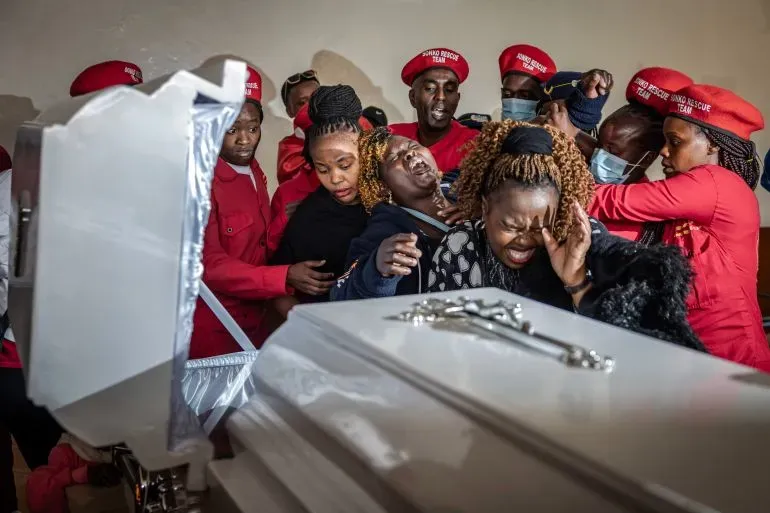 تظهر الصورة مشيعين حزانى في جنازة بونيفاس كاريوكي، بائع الأقنعة الذي قُتل على يد الشرطة، مع مظاهر الغضب والمطالبة بالعدالة.