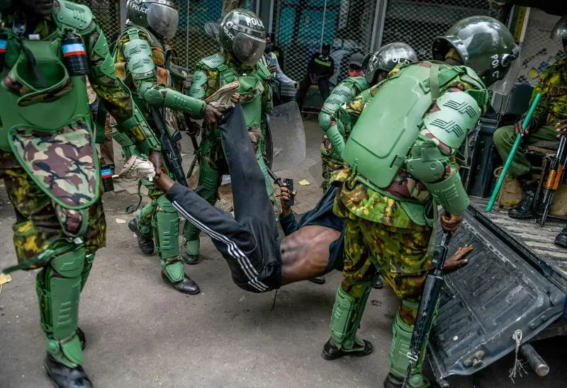 اعتقال رجل من قبل رجال شرطة يرتدون دروعًا واقية، حيث يبدو أنه مقيد ويتعرض للضغط أثناء عملية احتجاز في كينيا.