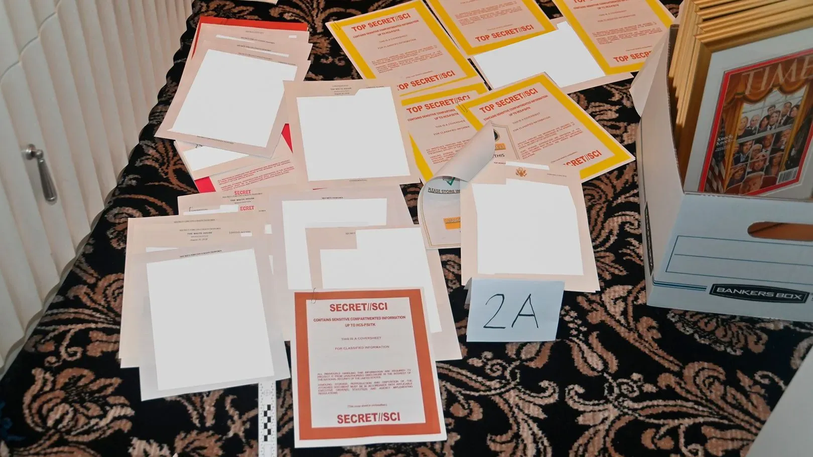 مستندات سرية متراكمة على طاولة، تتضمن أوراق تحمل علامات "سري" و"سري للغاية"، في سياق تحقيقات قانونية تتعلق بالرئيس ترامب.
