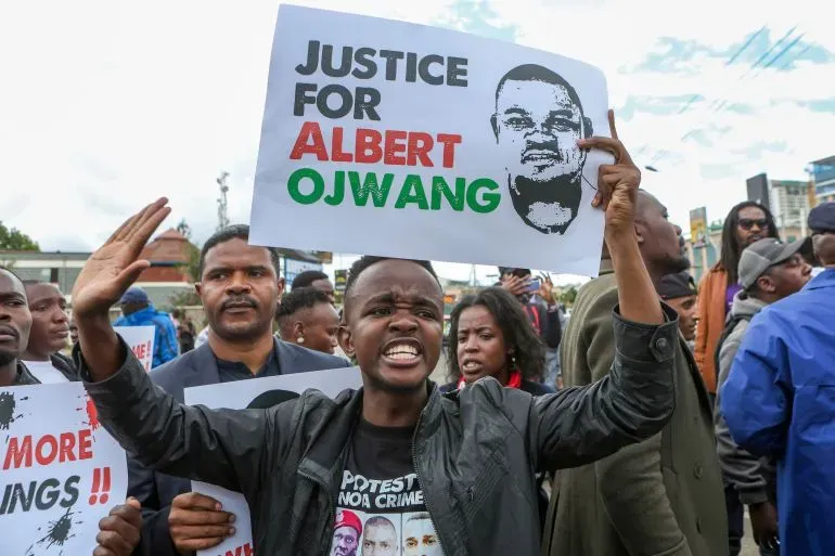 محتجون يحملون لافتات تطالب بالعدالة لألبرت أوجوانج، مع تعبيرات قوية عن الغضب والمطالبة بمحاسبة الشرطة في نيروبي.