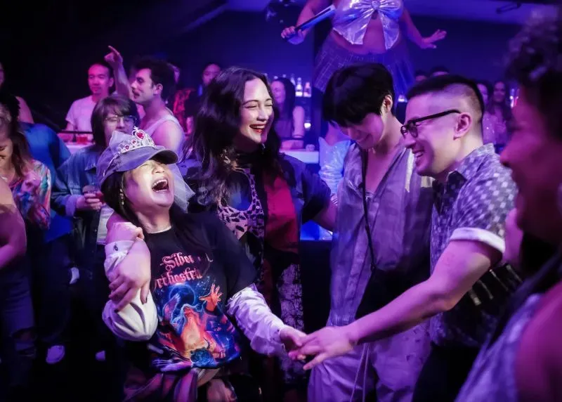 مجموعة من الأشخاص يحتفلون في حفل ليلي، مع أجواء مفعمة بالفرح والمرح، مما يعكس روح الانطلاق والتواصل الاجتماعي.