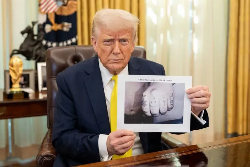 دونالد ترامب يحمل صورة توضح وشم كيلمار أبريغو غارسيا، الذي يُزعم أنه عضو في عصابة MS-13، خلال حديثه عن قضايا الهجرة في مكتبه.
