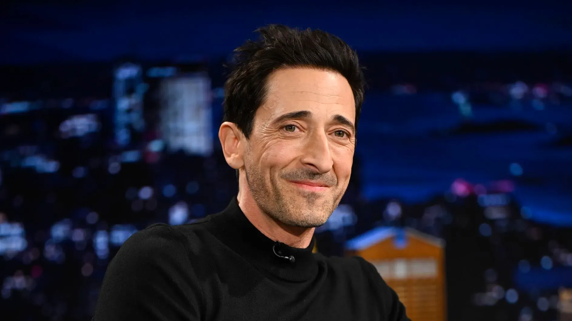 أدريان برودي مبتسم خلال ظهوره في برنامج "ذا تونايت شو"، حيث يتحدث عن تأثير كيم كارداشيان على نشاطه على إنستغرام.