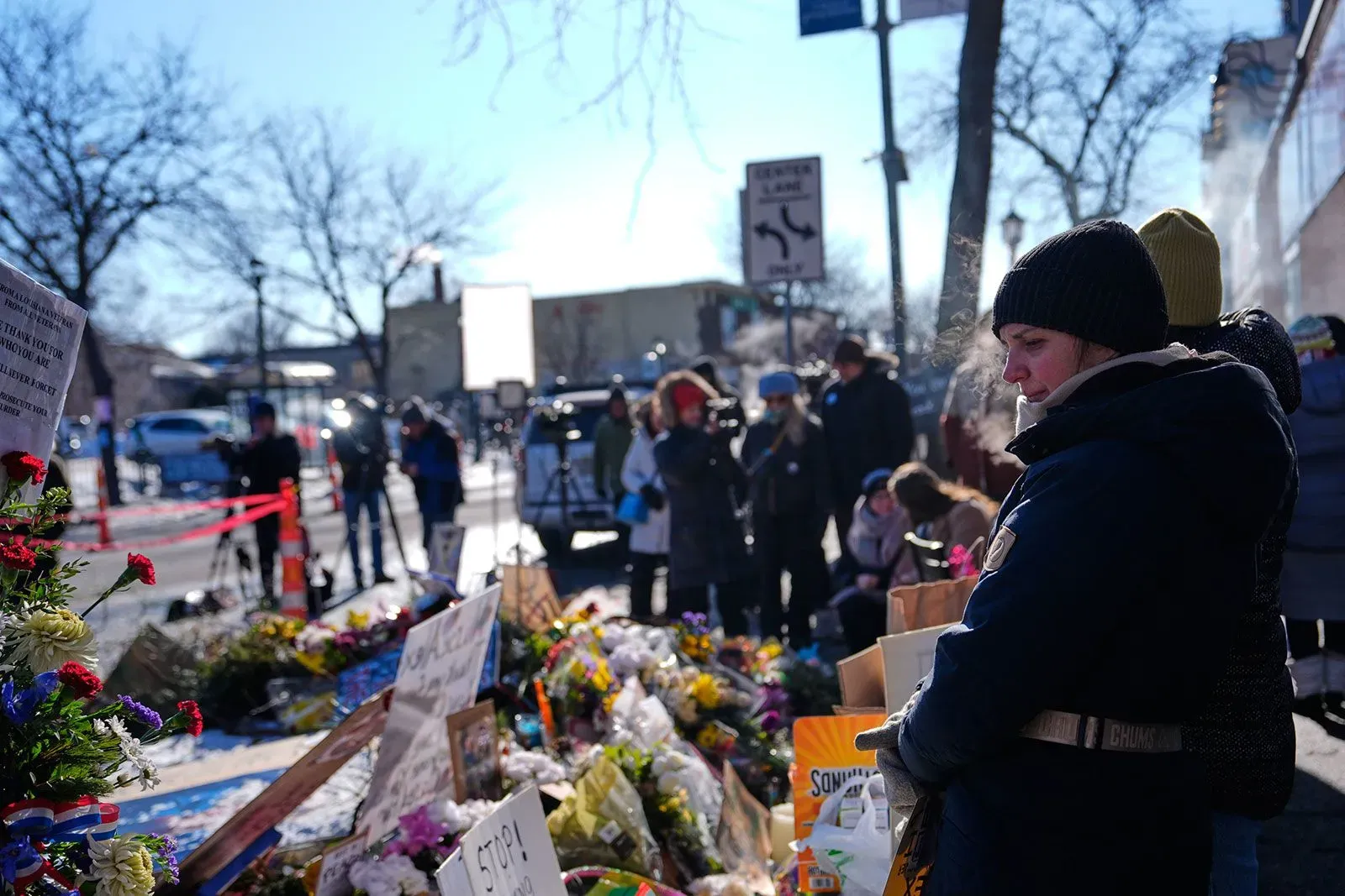 مجموعة من الأشخاص يتجمعون حول نصب تذكاري في الهواء الطلق، حيث يضعون الزهور والرسائل تخليداً لذكرى المتظاهر الذي قُتل.