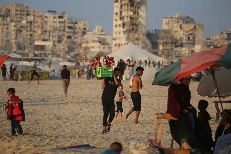 شباب فلسطينيون في غزة يمارسون حياتهم اليومية وسط المباني المتضررة، في ظل استمرار النزاع وتأثيرات خطة السلام الأمريكية.