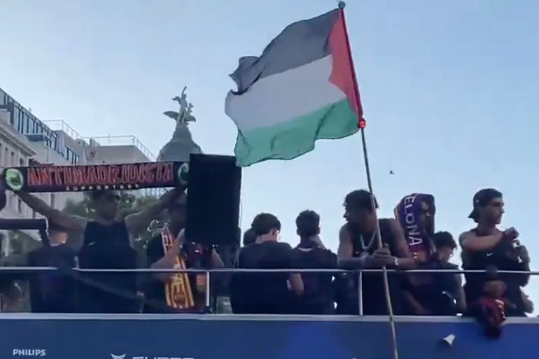لاعب برشلونة الشاب لامين يامال يرفع العلم الفلسطيني خلال احتفالات الفريق بلقب الدوري الإسباني في شوارع برشلونة.