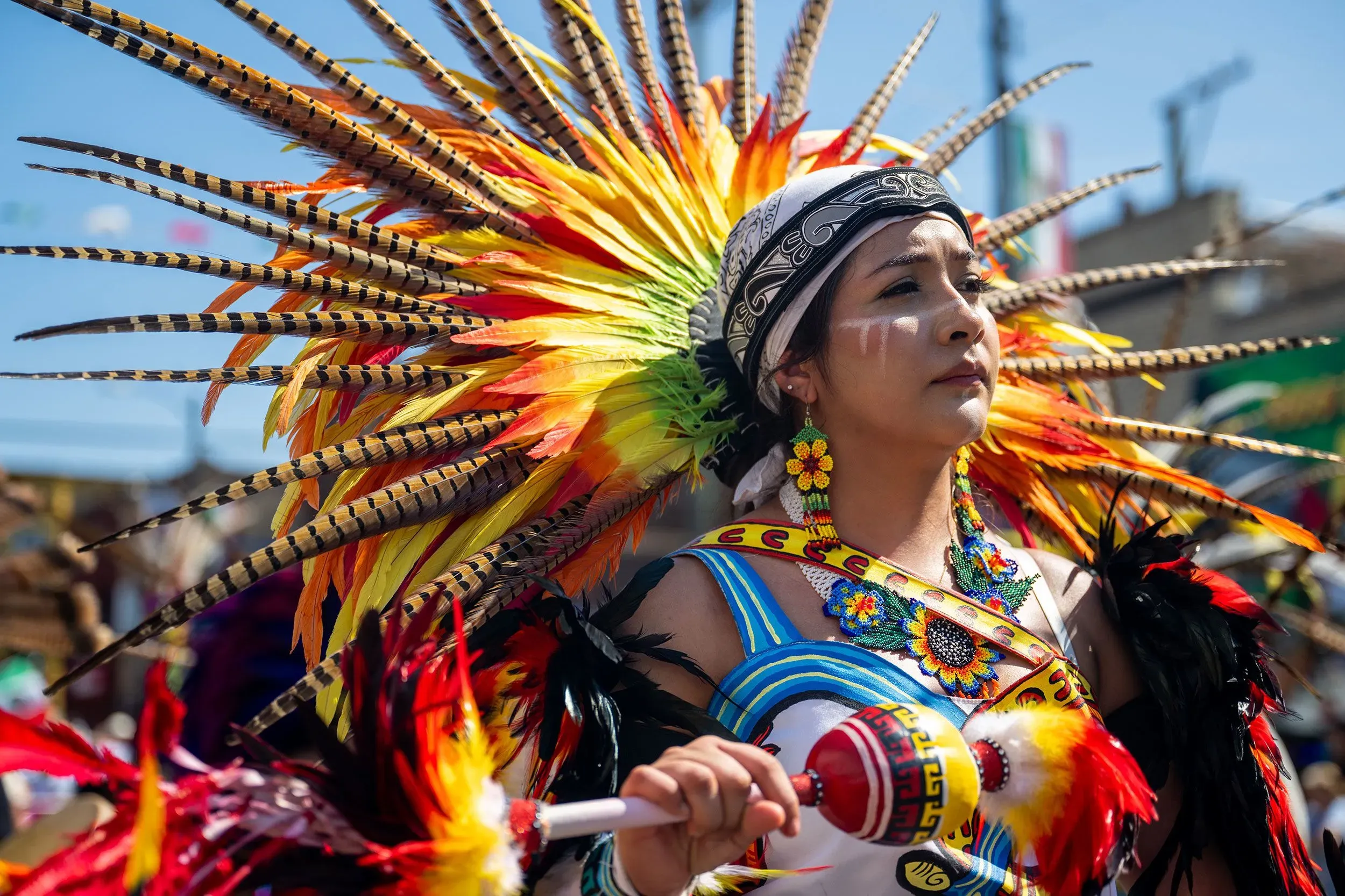 امرأة ترتدي زيًا تقليديًا ملونًا مع تاج من الريش، تشارك في احتفال يوم استقلال المكسيك، تعبيرًا عن الفخر والهوية الثقافية.