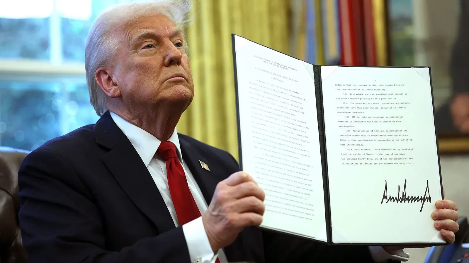 دونالد ترامب يحمل أمرًا تنفيذيًا في المكتب البيضاوي، مع تعبير جاد على وجهه، وسط أجواء رسمية.