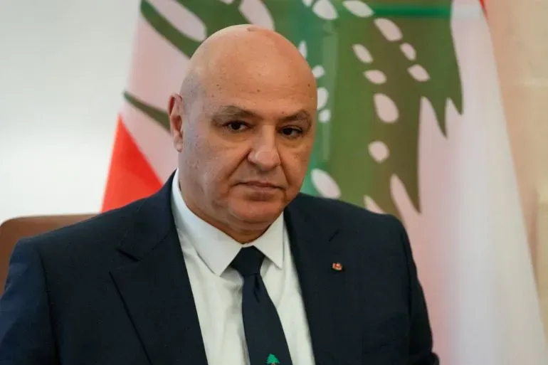 الرئيس اللبناني جوزيف عون يتحدث بجدية، مع العلم الوطني اللبناني خلفه، معبراً عن رغبة لبنان في السلام دون تطبيع العلاقات مع إسرائيل.