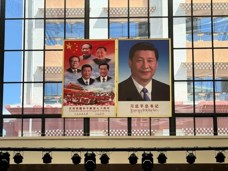 صور لافتات كبيرة تحمل صور الزعيم الصيني شي جين بينغ ومؤسسي الحزب الشيوعي، داخل مطار غونغغار في التبت، تعكس السيطرة السياسية والثقافية.