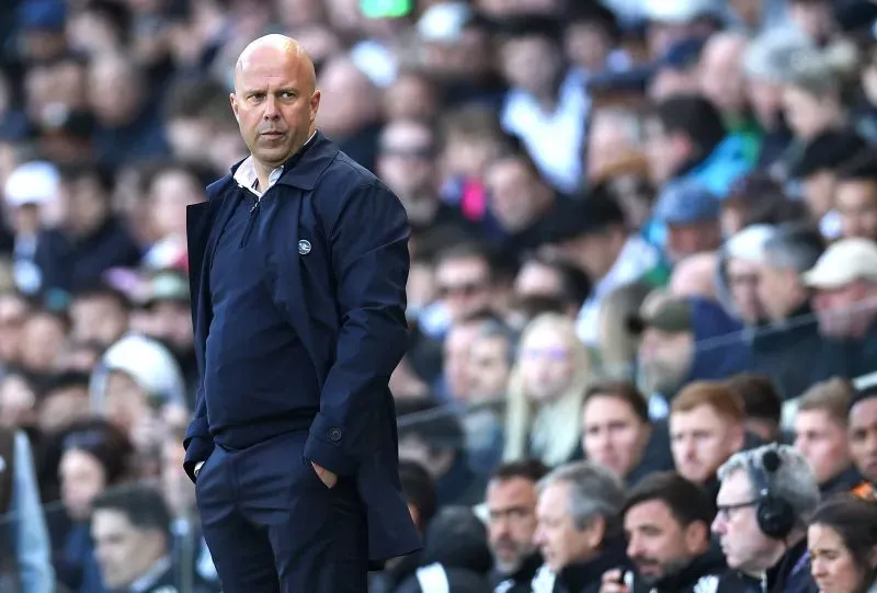 مدرب يقف على خط الملعب وسط حشد من المشجعين في ملعب أنفيلد، مع التركيز على الأجواء المشحونة خلال مباراة ليفربول.