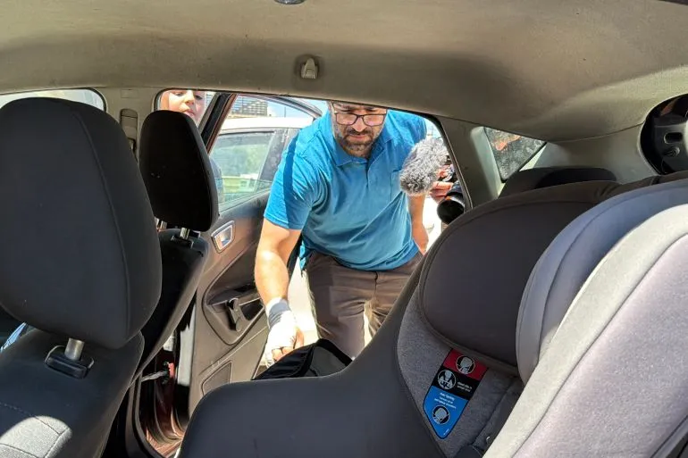 فهد أبو هيكل يفتش في السيارة بعد حادثة إطلاق النار التي أودت بحياة ابنه الرضيع سام، في الخليل. تُظهر الصورة مقعد الطفل الخلفي وأجواء الحادثة المأساوية.