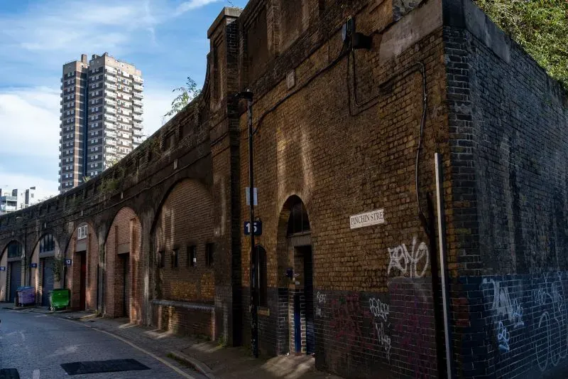 واجهة مبنى تاريخي في لندن، مع جدران من الطوب وأقواس، تعكس تأثيرات السياحة المظلمة في المنطقة.